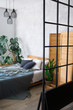 © sergiophoto - Cozy bedroom area at luxury studio apartment with a free layout in a loft style with big panoramic window and green plant.