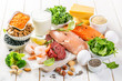 Selection of animal and plant protein sources - fish, meat, beans, cheese, eggs, nuts and seeds, kale, on wood background