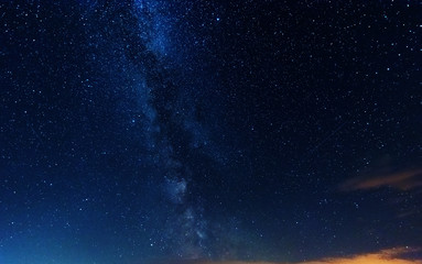 Wall Mural - a magical starry night on the river bank with a large tree and a milky way in the sky and falling st