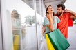 © NDABCREATIVITY - Young happy couple with shopping bags in the city, having fun together.