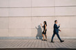 Business man and woman using smartphones and walking in opposite directions