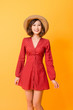 © makistock - Portrait of young beautiful asian woman  wear red dress and hat over orange background. Summer concept.