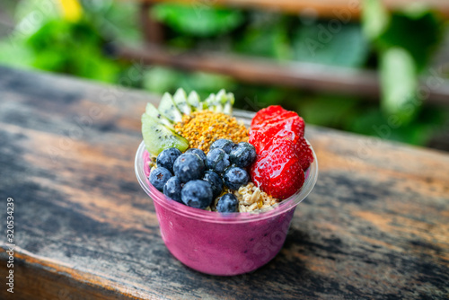 Acai bowl healthy breakfast in to go plastic takeout bowl frozen yogurt smoothie with fresh fruits, berries, blueberries at Hawaii cafe. Foodie food snack.
