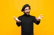 © kues1 - young french artist man feeling happy, astonished, lucky and surprised, like saying omg seriously? Unbelievable against orange wall