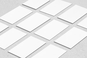 Closeup of empty white rectangle business card mockups lying diagonally on neutral grey concrete background. Flat lay, isometric view. Open composition. Blank Template for Corporate Identity