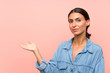 Young woman over isolated pink background holding copyspace imaginary on the palm