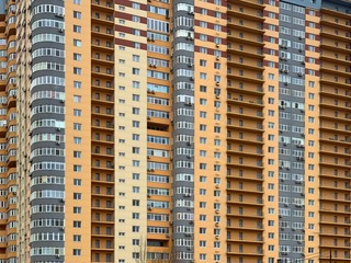 Background texture: multi-storey new house. Tall yellow-gray building in a new area. Concept: real estate investment, mortgage, new building.