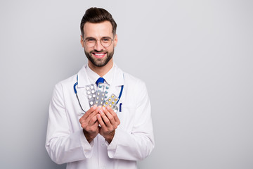 Close-up portrait of his he nice attractive glad cheerful cheery skilled professional doc holding in hands plates of tablets therapy solution isolated on light white gray pastel color background