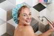 © Drobot Dean - Image of young woman smiling while taking shower in bathroom at home