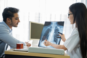 Asian female doctors with patients look at the X-ray to examine the results of patients' health examinations in the office.