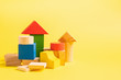 © ximich_natali - Children's wooden toys on a yellow background concept zero west. Small houses the designer from developing color cubes