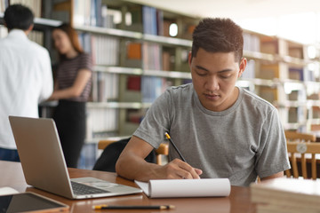 Wall Mural - male asian student studying and reading book in library