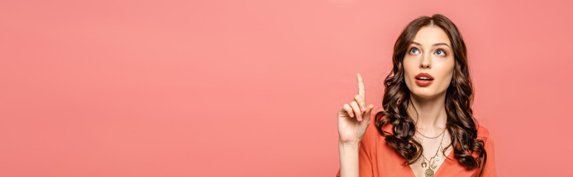 panoramic shot of thoughtful young woman showing idea gesture while looking up isolated on pink