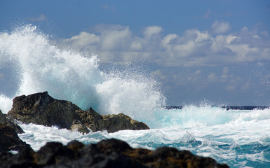  Big waves beating against rock shore of Sao Miguel island, Azores. Water splash, background of blue ocean, cloudy sky