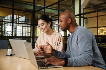 image of multiethnic young coworkers working on laptops in office