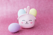 Easter Bunny Bag With Eyes, Nose, Mouth With Colorful Eggs: Purple, Yellow And Blue On A Pink Sparkling Background. The Hare Is A Symbol Of A Religious Holiday And Catholics, Orthodox And Protestants