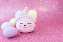Easter Bunny Bag With Eyes, Nose, Mouth With Colorful Eggs: Purple, Yellow And Blue On A Pink Sparkling Background. The Hare Is A Symbol Of A Religious Holiday And Catholics, Orthodox And Protestants