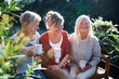 Senior women friends with coffee sitting outdoors on terrace, resting.