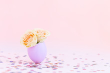 Purple Easter Eggshell With Yellow,orange,beige Pastel Small Roses On Pink Background, Multicolor Confetti. Egg Is Symbol Of Celebration Of A Religious Holiday Among Catholics, Christians,Protestants