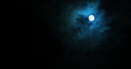 full moon on dark cloudy night. clouds passing by the moon in spooky feeling like thriller and horro