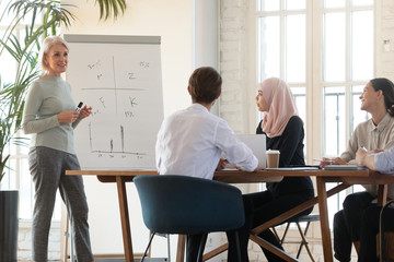 Canvas Print - Middle-aged female coach make presentation for diverse colleagues