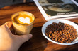 topview hot espresso on hand, placed on a wooden table, placed beside coffee beans