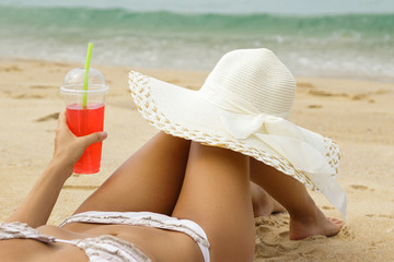 Wall Mural - Woman with a red refreshing drink on the beach