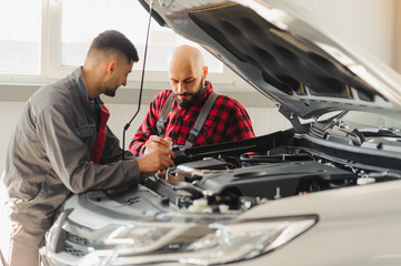 auto service, repair, maintenance and people concept - mechanic men with wrench repairing car engine at workshop