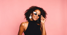 Beautiful African American Girl With An Afro Hairstyle Smiling. Portrait Of Happy Young Black Woman Laughing Against Pink Wall.Blissful Lovable Woman With African Hairstyle Laughing Indoor