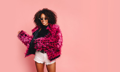 Wall Mural - Black woman in a black faux fur jacket, Close up fashion portrait of crazy hipster African girl with funny curly hairstyle and vivid faux fur coat, urban trendy style. Horizontal.copy space