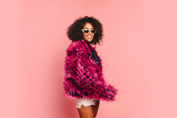 Black woman in a black faux fur jacket, Close up fashion portrait of crazy hipster African girl with funny curly hairstyle and vivid faux fur coat, urban trendy style. Horizontal.copy space