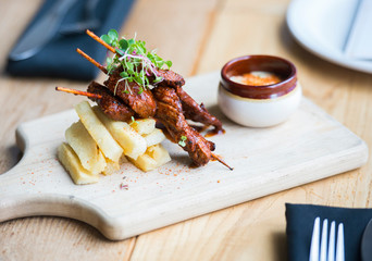 Anticucho Beef skewers with Yuka fries and tari sauce are shown on a table in a restaurant