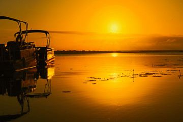 Sunrise over lake Bacalar with two tour boats in the foreground