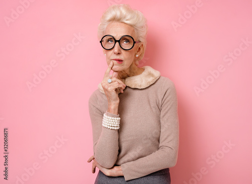 Pensive grandma being deep in thoughts, curves lips, holds chin and looks away Tableau sur Toile