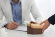 © New Africa - Woman giving bribe to man at table in office, closeup