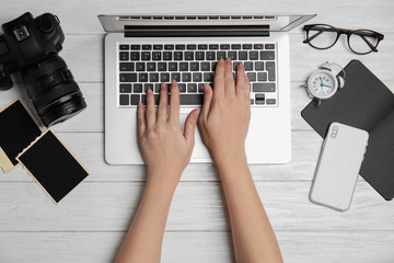 Designer working with laptop at white wooden table, top view