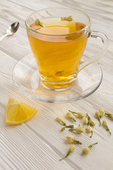 Wall Mural - Jasmine green tea in the glass cup on the white wooden background. Location vertical.