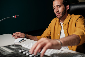 Wall Mural - Man working on music controllers at home studio