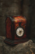 © Alberto Ortega/ADDICTIVE STOCK - Aged antique watch in red box vintage clock with classical dial on stone in street