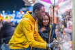 © Javier De La Torre/ADDICTIVE STOCK - African American woman smiling and watching boyfriend catching toys in arcade game while spending evening on funfair together