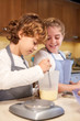 © PHILIPPE DEGROOTE/ADDICTIVE STOCK - Vertical stock photo of a boy stirring milk to prepare cupcakes with a girl next to him looking smiling