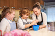 © PHILIPPE DEGROOTE/ADDICTIVE STOCK - Stock photo of a boy with apron breaking an egg in the kitchen with a blonde girl and a girl next door preparing cupcakes