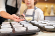 © PHILIPPE DEGROOTE/ADDICTIVE STOCK - Stock photo of a plates prepared with pastry paper for cupcakes with the detail of a hand taking out cream with a portioned Ice cream scoops
