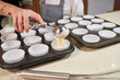 © PHILIPPE DEGROOTE/ADDICTIVE STOCK - Stock photo of a hand of a girl emptying cream with the ice cream scoops in plates prepared with pastry paper for cupcakes