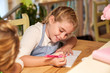 © PHILIPPE DEGROOTE/ADDICTIVE STOCK - Stock photo of a girl sitting in front of a wooden table writing in a notebook and with a notebook and flowers in front of her