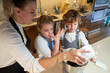 © PHILIPPE DEGROOTE/ADDICTIVE STOCK - Stock photo of two boys and a girl with apron in the kitchen mixing ingredients preparing cupcakes