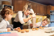 © PHILIPPE DEGROOTE/ADDICTIVE STOCK - Stock photo of a girl wearing an apron putting cream on top of a cupcake with a pastry sleeve with two children on the side watching