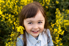 A Little Girl In A Field Of Flowering Yellow Rapeseed. Rapeseed Field. Girl With Yellow Flowers