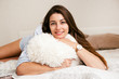 © zadorozhna - Young smiling woman lying with pillow in bed in her bedroom. Happy morning.