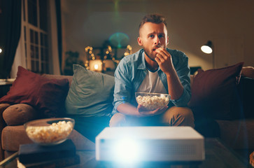 Wall Mural - young man watching projector tv at home in   evening alone.